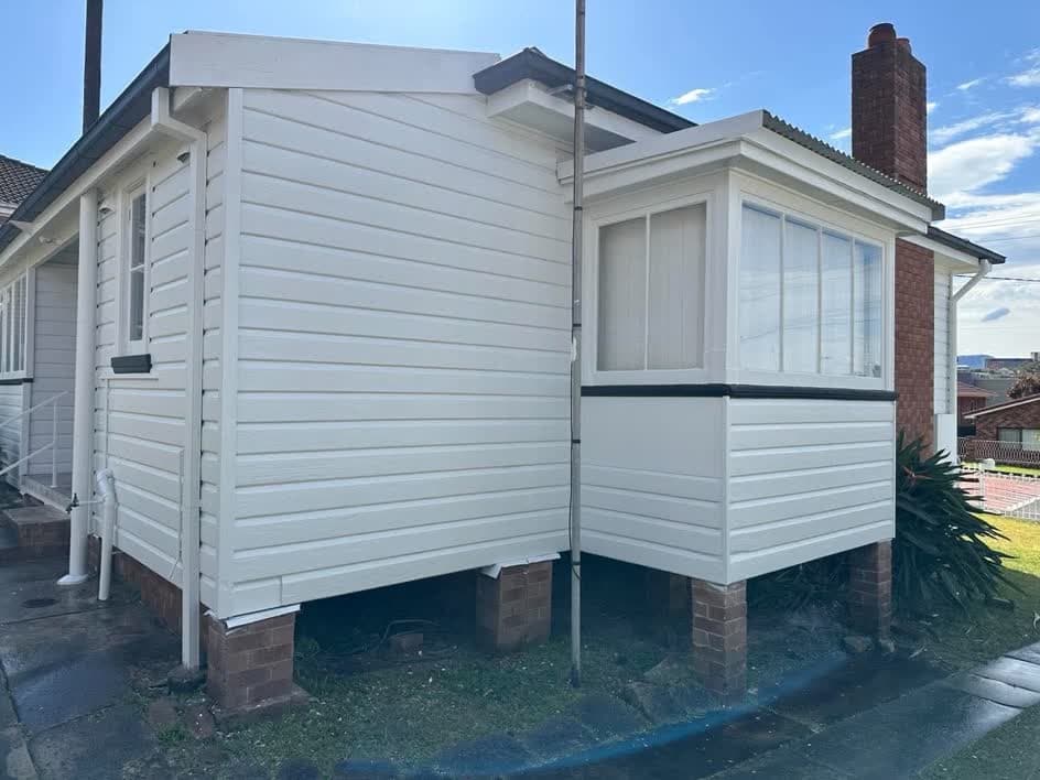 The same weatherboard house repainted in white with black trim